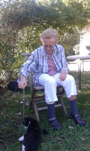 Personne âgée assise dans un jardin qui joue avec un chat
